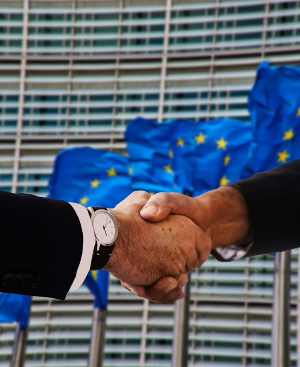 Photo of shaking hands in front of EU flag